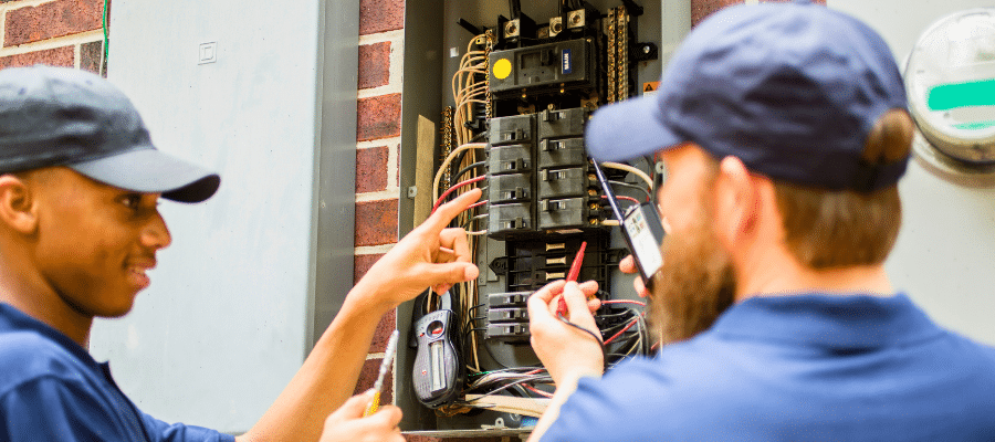 Electricians inspecting an outdoor residential electrical panel