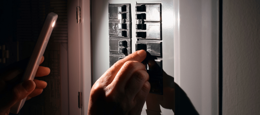 Person resetting a circuit breaker at a residential electrical panel